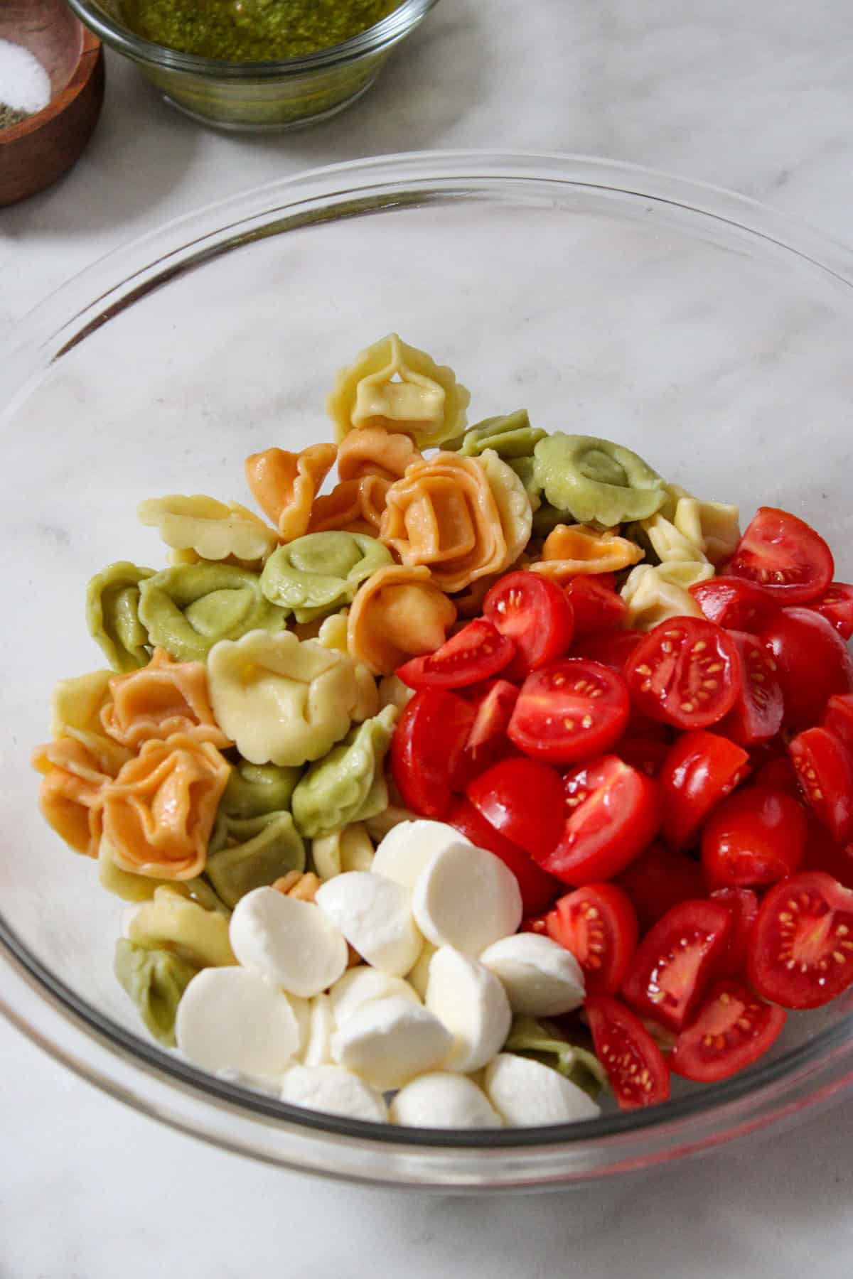 multi-colored tortellini, fresh cherry tomatoes and mozzarella balls in a glass bowl