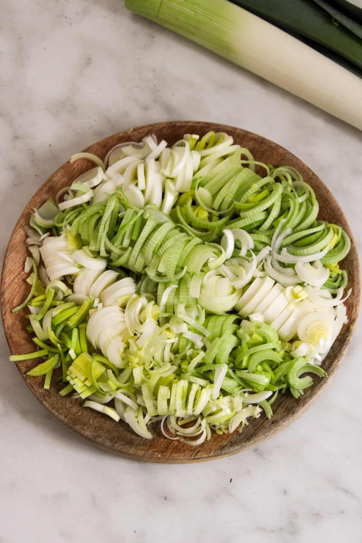 green and white sliced leeks on a wooden plate