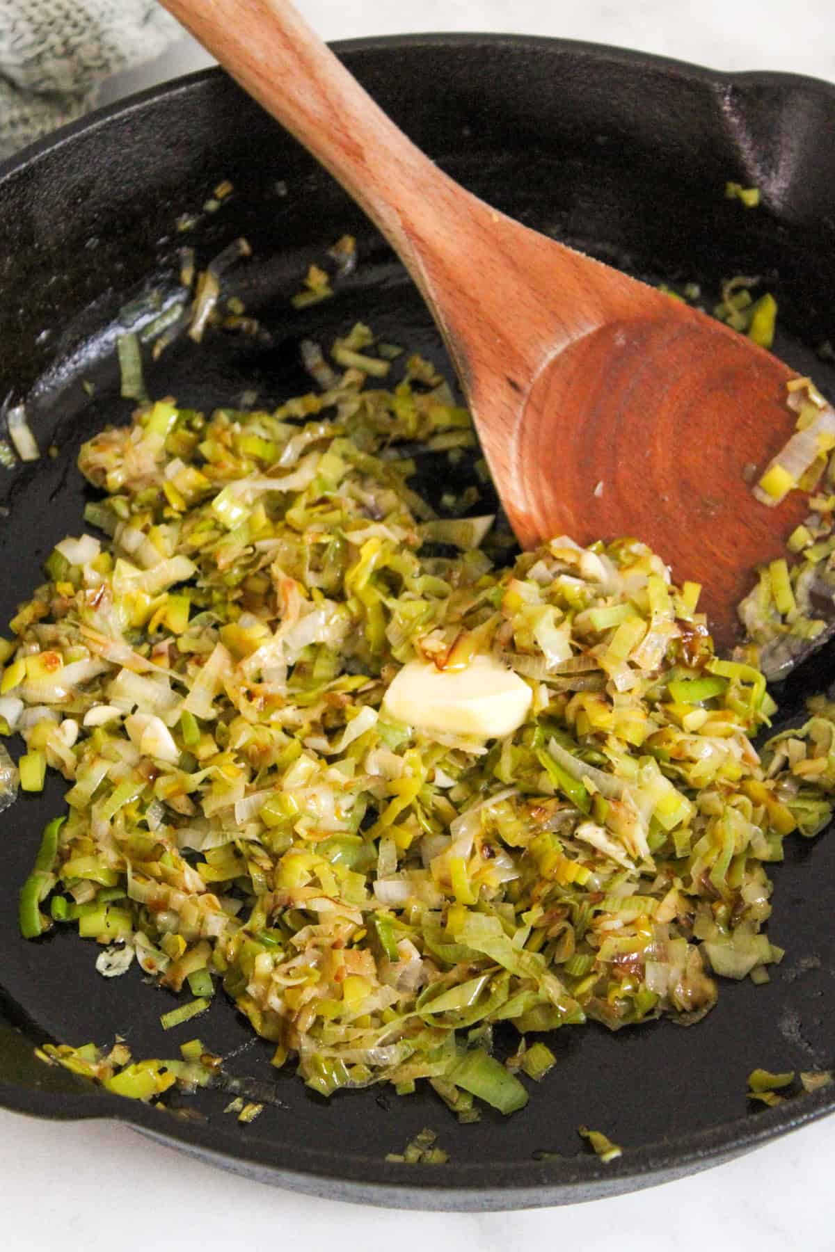 caramelized leeks in a black cast iron skillet with a wooden spoon