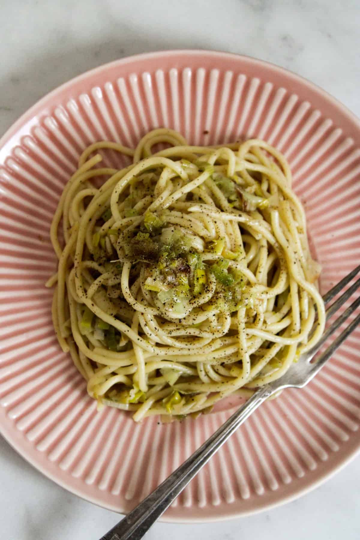 caramelized leek pasta on a pink plate with a fork