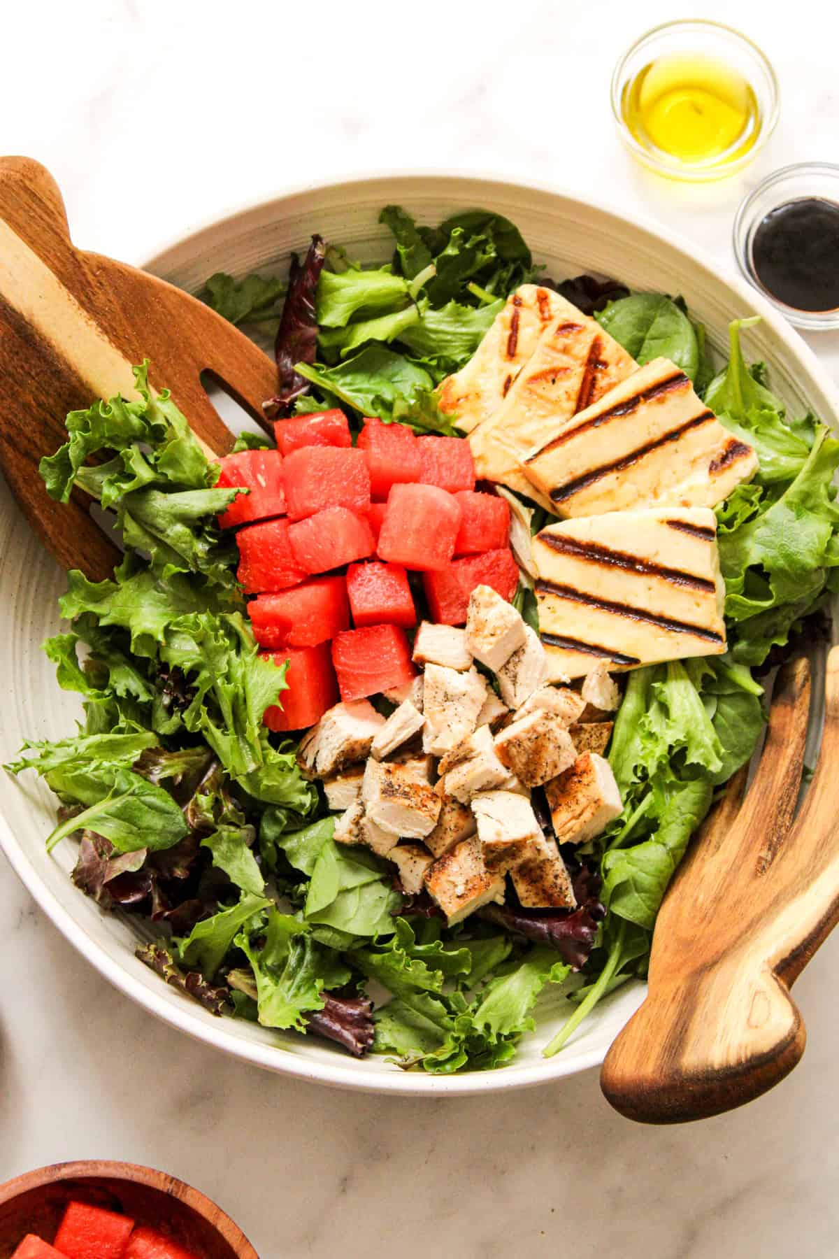 overhead shot of salad in a ceramic bowl with wooden salad tongs