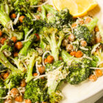 tahini caesar broccoli salad in a ceramic bowl with lemon wedges