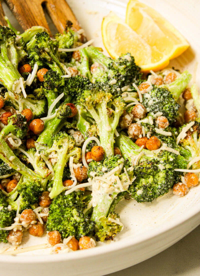 tahini caesar broccoli salad in a ceramic bowl with lemon wedges