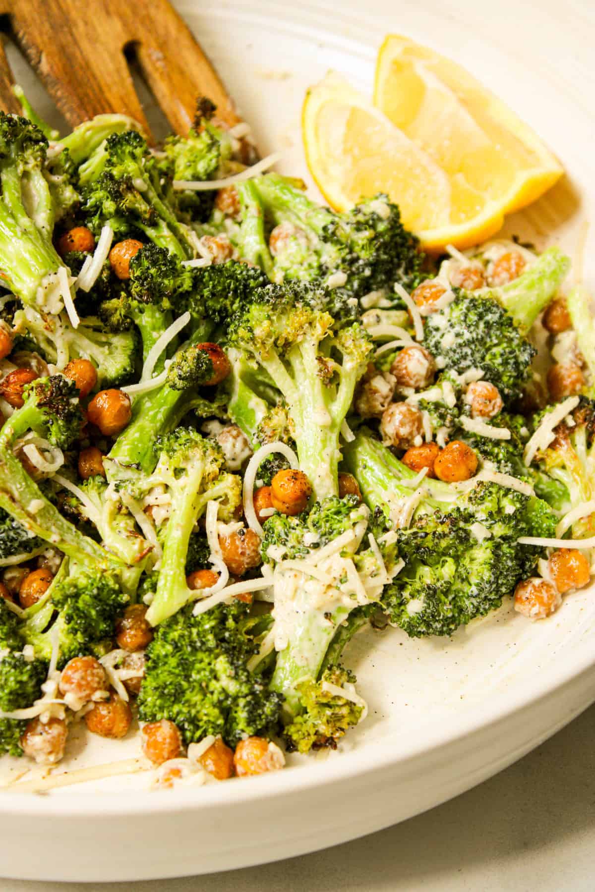 tahini caesar broccoli salad in a ceramic bowl with lemon wedges