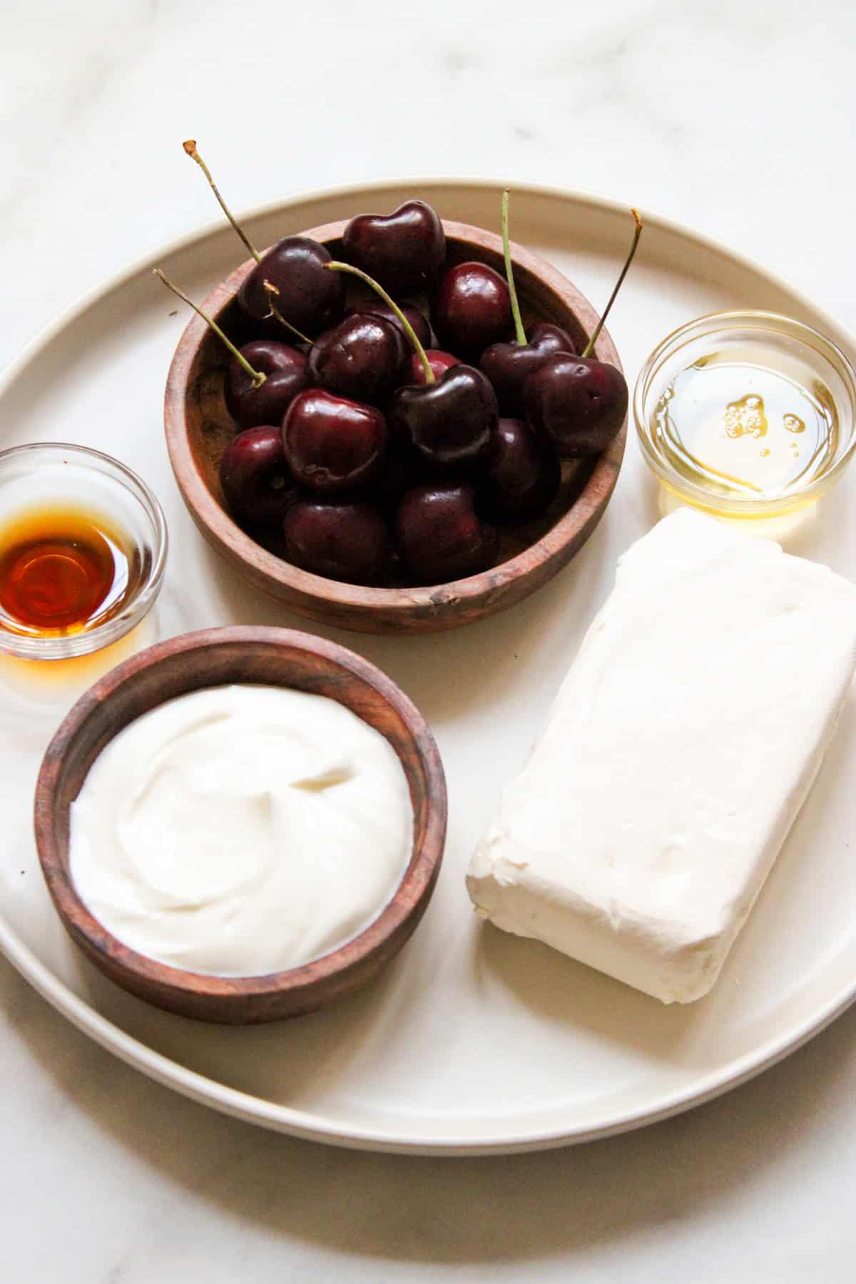 ingredients for cheesecake dip in small bowls arranged on a beige plate