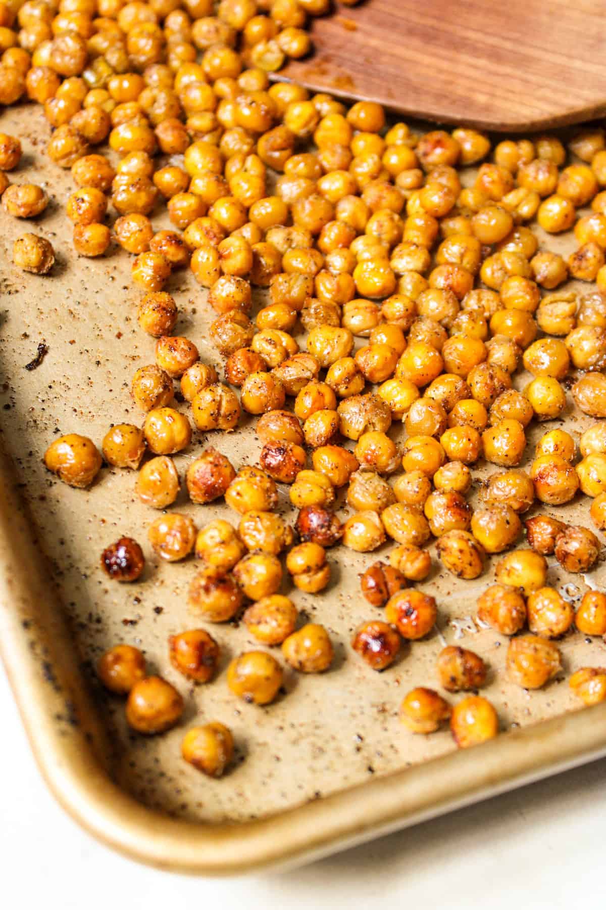 close up shot of crispy golden chickpea croutons on a baking sheet with a wooden spatula