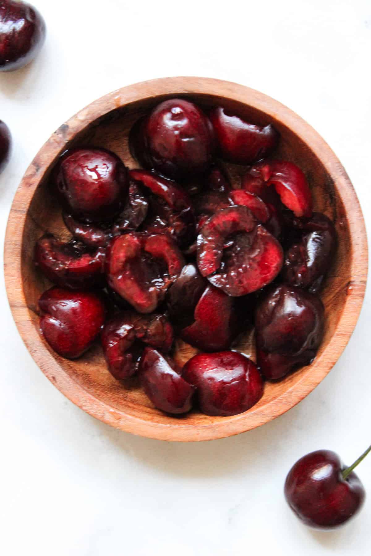 close up overhead shot of pitted and sliced cherries in a small wooden bowl