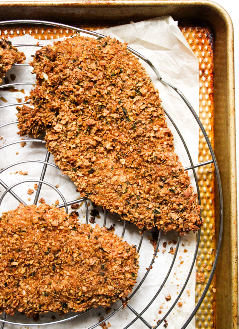 golden brown breaded baked chicken cutlet on a wire rack and baking sheet