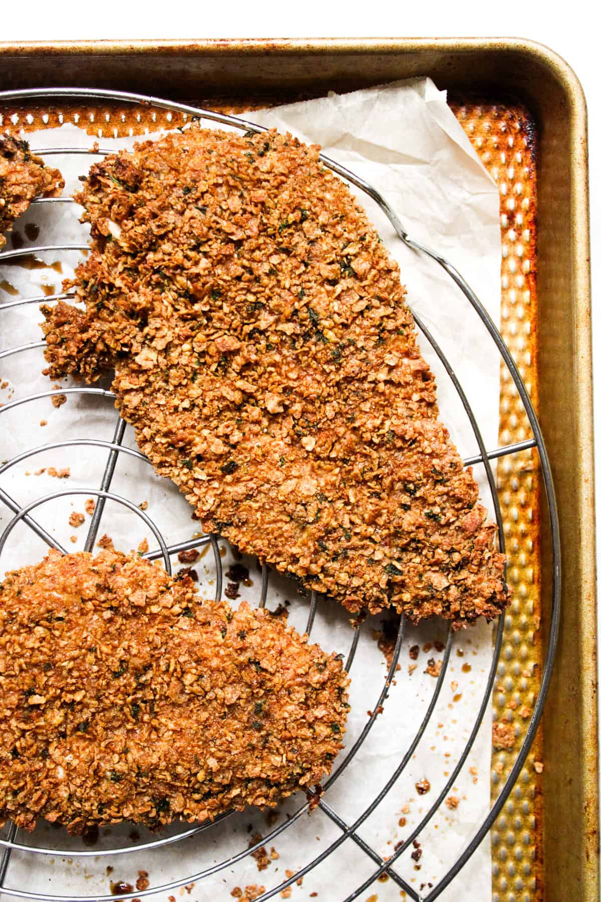 golden brown breaded baked chicken cutlet on a wire rack and baking sheet